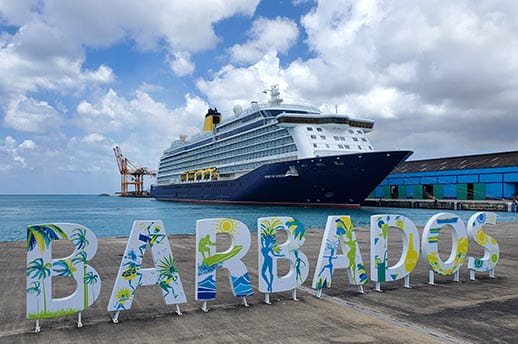 A view from land of the Spirit of Discovery in port, behind Barbados sign.